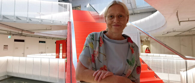 Präsidentin der Filmuni, Prof. Dr. Susanne Stürmer vor roter Treppe in Haus 6 